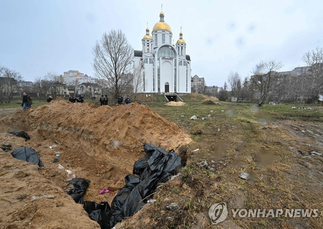 <strong>러군의 민간인 학살 의혹 키우는 우크라 집단매장지</strong><br>
(부차 AFP=연합뉴스) 러시아군이 한 달 넘게 점령했던 우크라이나 수도 키이우(키예프) 북서쪽 소도시 부차의 한 교회 앞에 조성된 민간인 희생자 집단 매장지 주변의 3일(현지시간) 모습. 구덩이 안에는 시신을 담은 검은 자루 같은 것이 보인다. 우크라이나 정부와 서방 국가들은 러시아군이 부차에서 민간인을 학살한 뒤 묻었을 가능성이 있는 이 매장지가 발견된 뒤 러시아군이 전쟁범죄를 저질렀다고 비난하며 국제형사재판소(ICC)에서의 처벌을 주장하고 나섰다. 아나톨리 페도루크 부차 시장은 AFP 인터뷰에서 지금까지 집단 묘지에 묻힌 것으로 확인된 시신이 280구라고 말했다. 한 구조요원은 교회 뒤쪽에 서둘러 판 한 참호에서만 57구의 시신이 발견됐다고 전했다. 2022.4.4