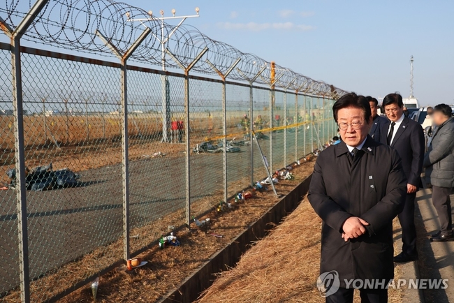  더불어민주당 이재명 대표가 1일 오후 전남 무안군 무안국제공항 제주항공 여객기 참사 현장 외곽 울타리에서 수색 현장과 시민<br>
들이 남긴 추모 물품을 보고 있다. 2025.1.1 【무안=연합뉴스】